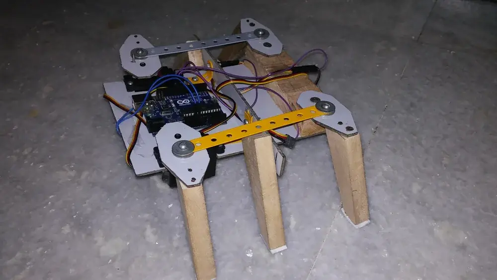 A six-legged experimental robot with wooden legs, metal linkages and an exposed Arduino controller.