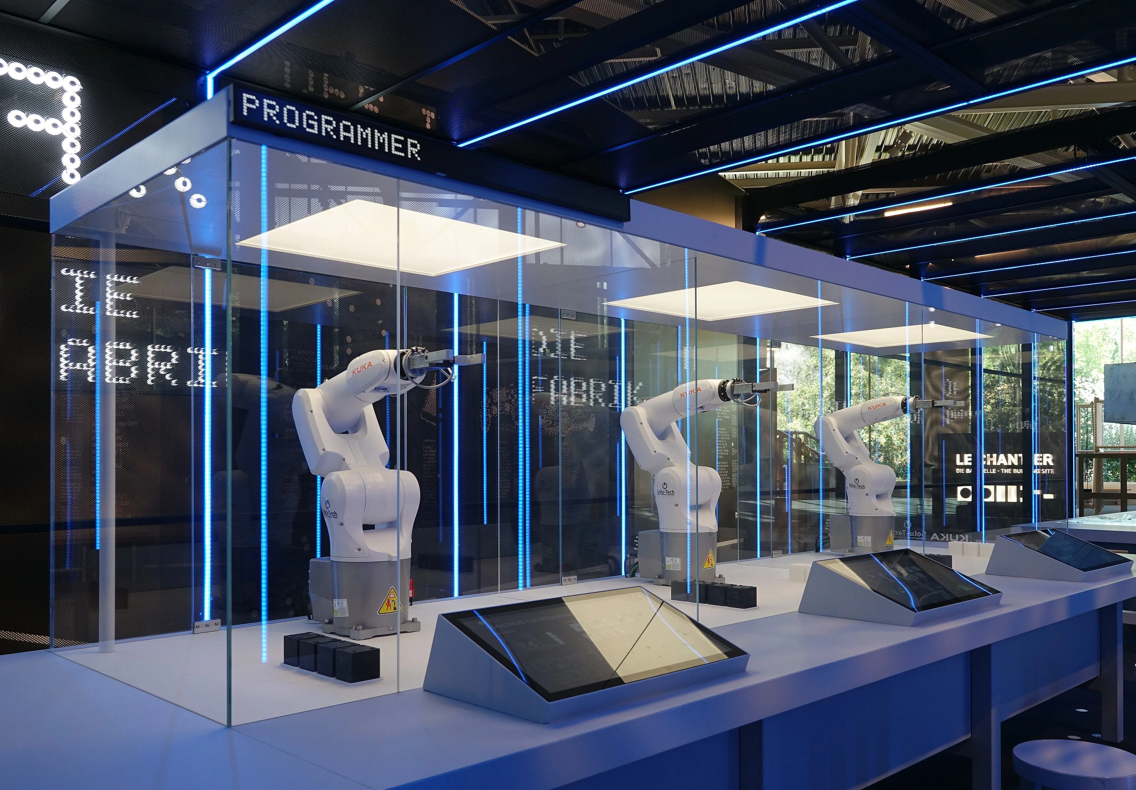Three white industrial robotic arms behind glass at Le Vaisseau in Strasbourg