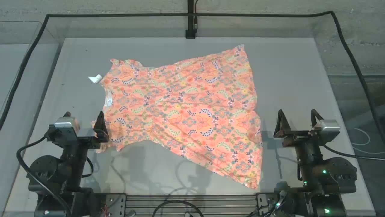 Two robot grippers manipulate a patterned cloth in a Dream Labs Dream-1 demonstration.
