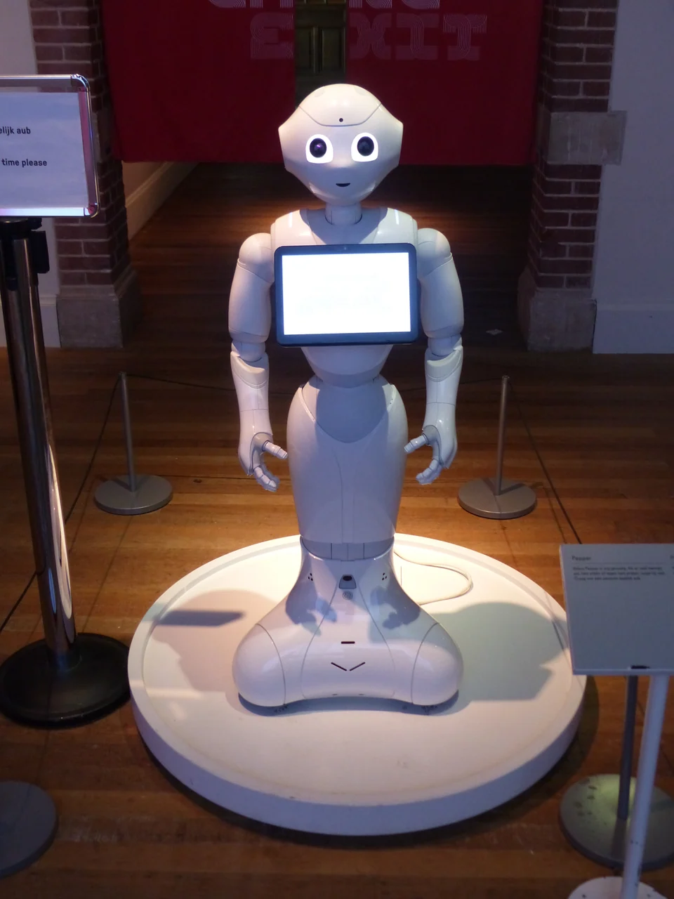 White Pepper social robot with expressive eyes and a chest-mounted tablet in a museum.