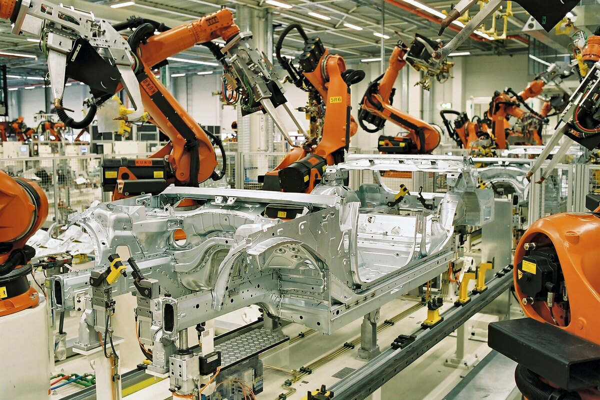 KUKA industrial robots spot-welding car bodies at BMW's Leipzig factory (2005); illustrative automation photograph.